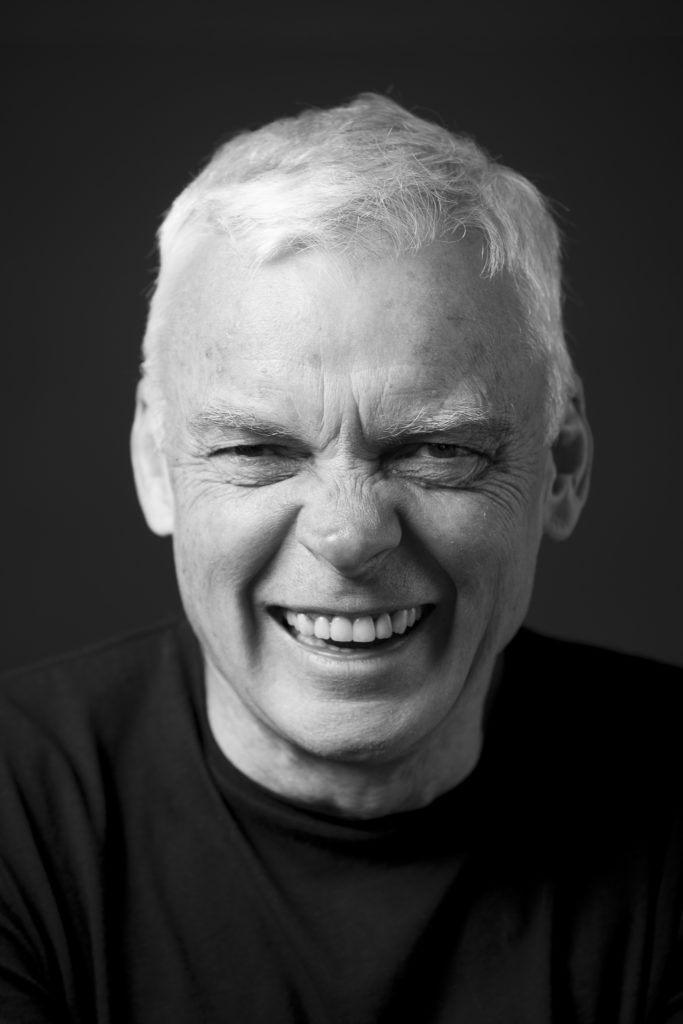 Black-and-white portrait image of Graeme Simsion smiling