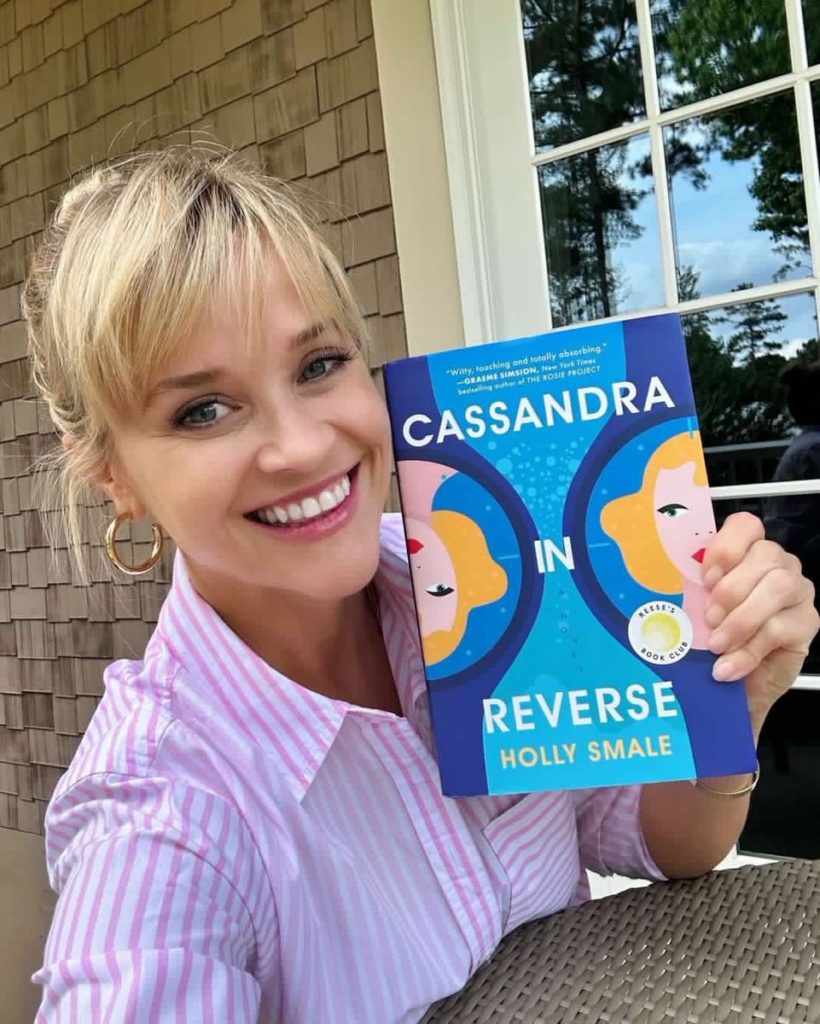 Holly Smales holding her book, Cassandra in Reverse, with Graeme Simsion's endorsement on the cover: 'Witty, touching and totally absorbing.'